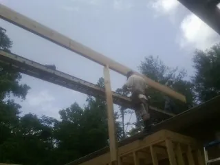 Carpenter setting a ridge beam over a new addition frame — Ice Dam Removal by Roofing Brothers in Jeanerette