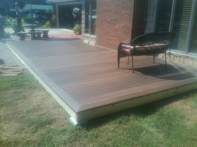 New wood deck and wicker chair beside a brick house in Jeanerette