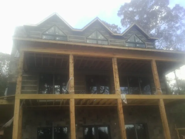 Dormers and porch framing on a large log home under construction — Roof Coating work by our crew in Jeanerette