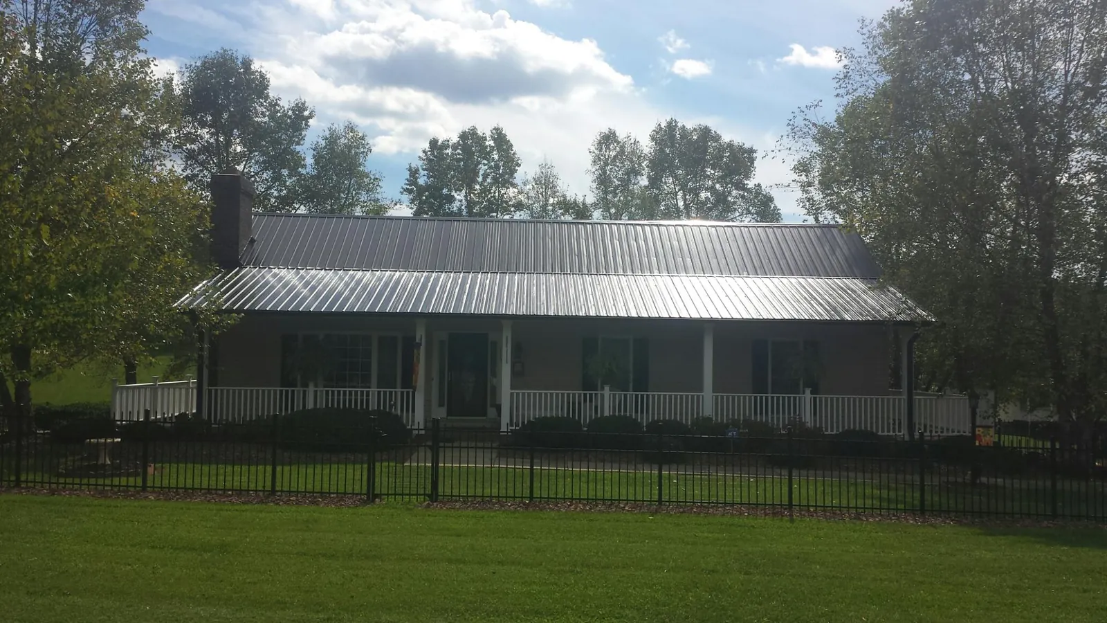 Gray metal roof on a brick ranch with a full width front porch — Gutter Guard Installation work by our crew in Jeanerette