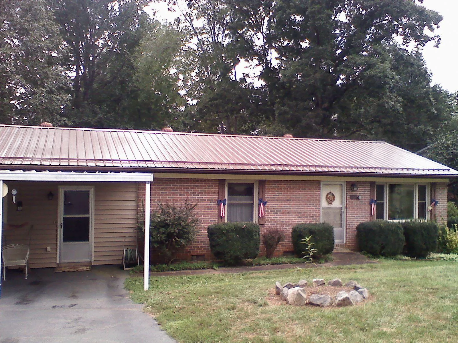 Bronze metal roof and carport on a brick ranch home — Roof Repair work by our crew in Jeanerette