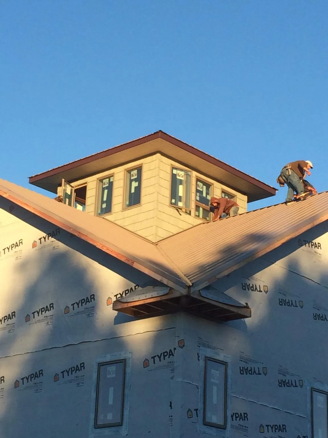 Roofers working around a rooftop cupola on a new metal roof at sunset — Roof Waterproofing in Jeanerette by Roofing Brothers